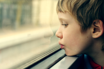 sad kid with autism watching at the glass window