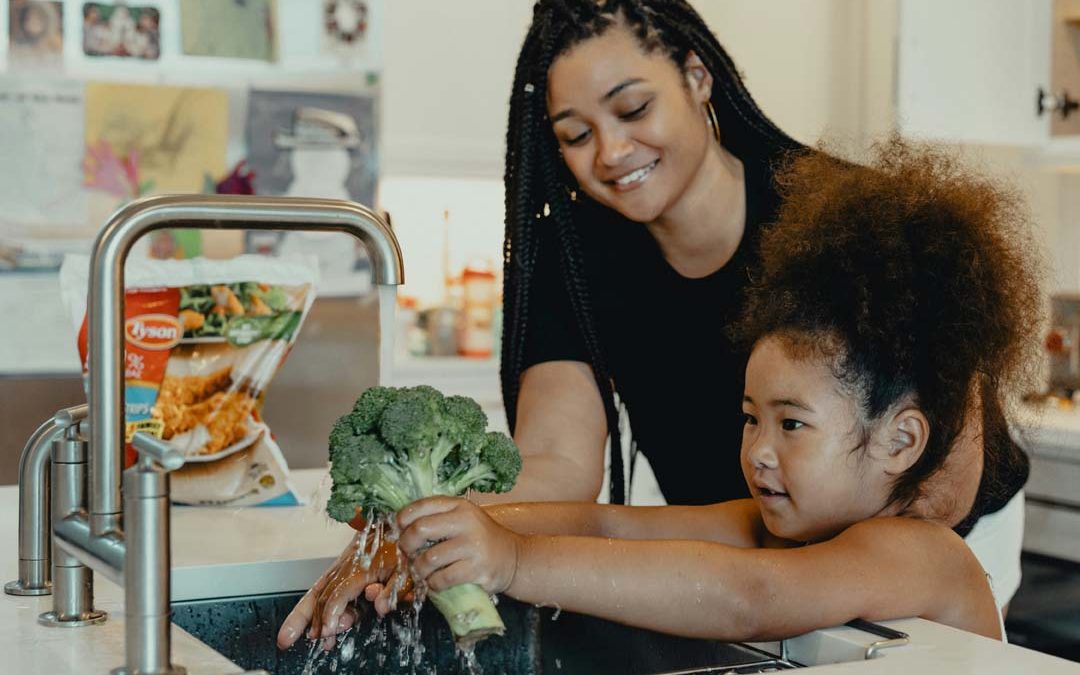 mom-teaching-daughter-to-wash-vegetables-by-tyson-at-unsplash
